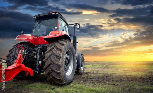 Agricultural tractor working in the field at sunset background photo