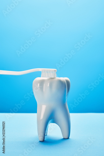 close up view of tooth model and toothbrush on blue background, dentistry concept