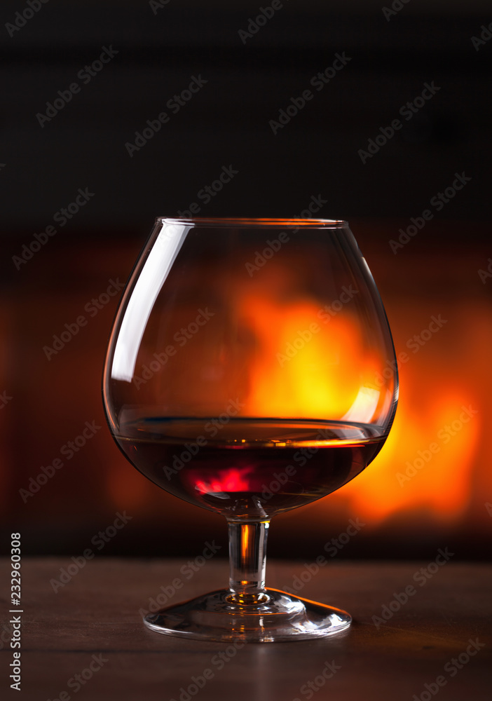 glass of cognac in front of fireplace glass of cognac in front of fireplace