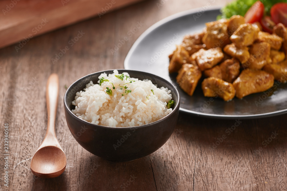 White rice with curry and chicken in black plate on wooden table White rice with curry and chicken in black plate on wooden table
