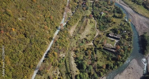 pictorial aerial view river with ruined bridge and road meandering between forestry hills near ghost town on autumn day photo