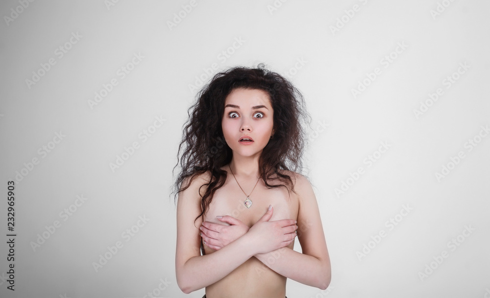Fototapeta premium The girl covers her chest with his hands on a white background. Girl showing emotion
