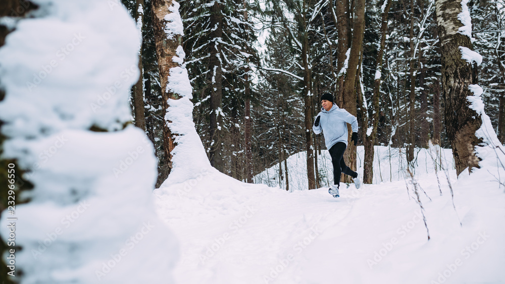 Young healthy man running in forest at winter Young healthy man running in forest at winter