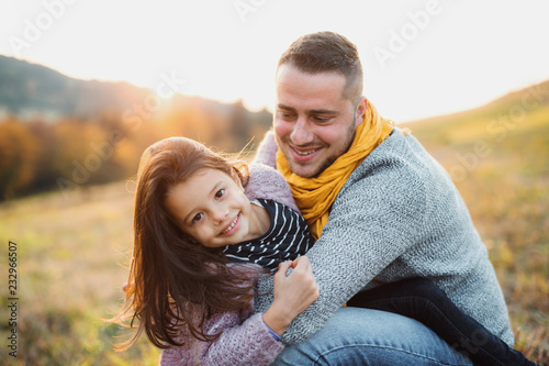 A young father having fun with a small daughter in autumn nature.