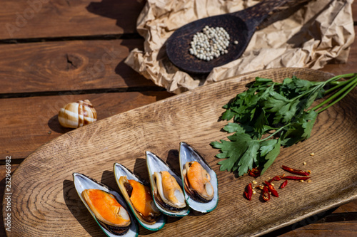 Delicious seafood mussels with sauce, red pepper and parsley. Clams in the shells on a wooden table
 photo