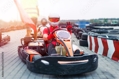 Go-Kart racing car on the track in action, championship, active sports, extreme fun, the driver keeps his hands on the wheel. driver protective gear. day, karting photo