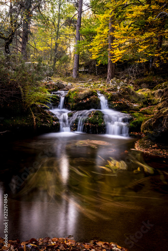 cascadas de sedas en río en otoño con hojas y piedras