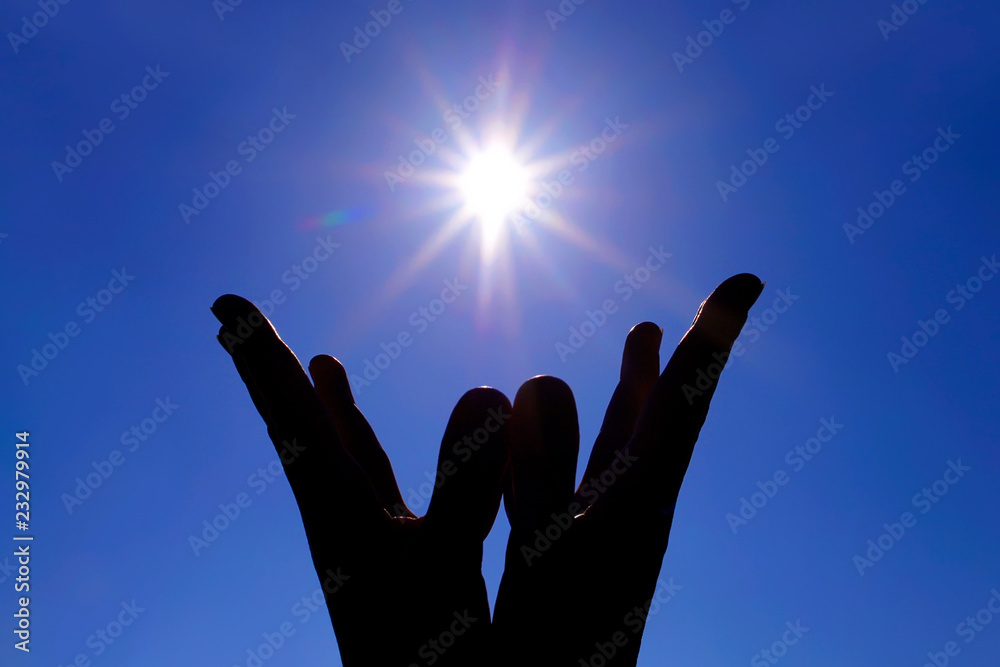silhouettes of hands and fingers of a young woman united in mudras. on blue sky background. sunshine. yoga fingers. lotra mudra.