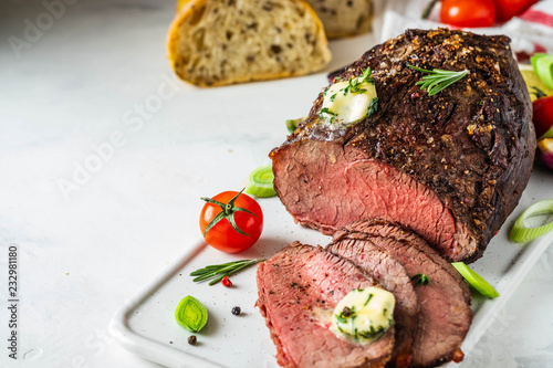 Roast beef with sauce and meat fork on white background. Copy space.