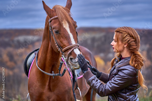 Portrait of a young beautiful woman with long brown hair. Woman on a horse walk in the forest.