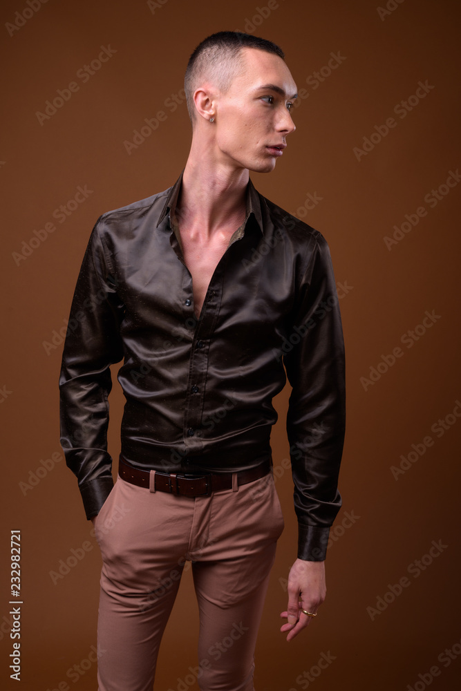 Young handsome androgynous businessman against brown background Young handsome androgynous businessman against brown background