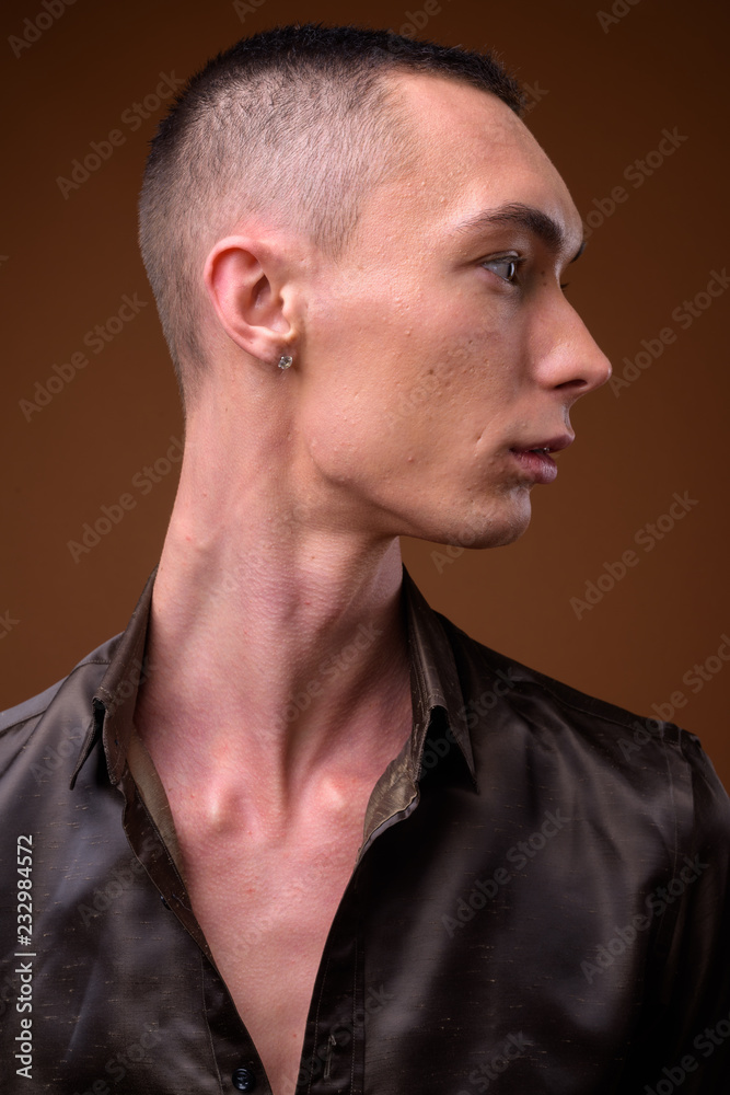 Fototapeta premium Young handsome androgynous businessman against brown background