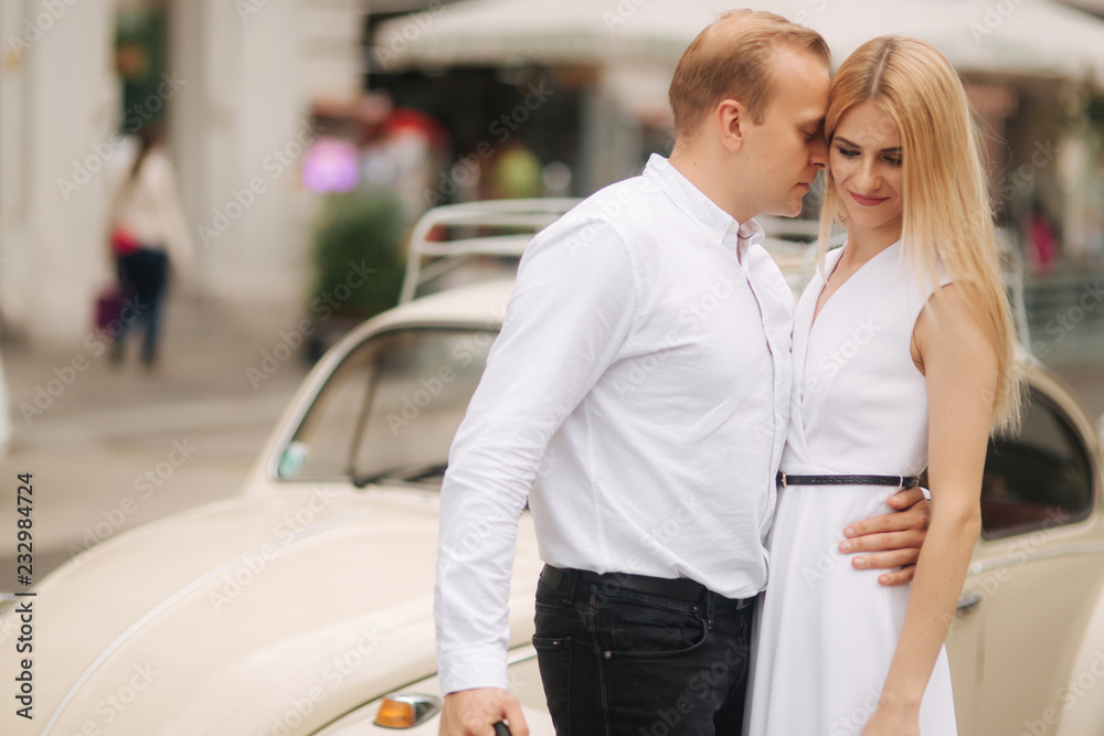Man and woman stand near their car with umbrella. Beautiful couple in the city. Black umbrella. Black and white clothes