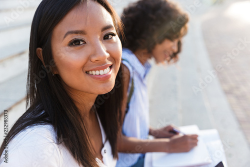 Smiling asian girl sitting on stairs outdoors photo