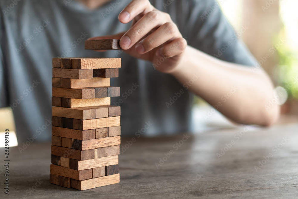The risk will happen.Hand of engineer playing a blocks wood game on wood table vintage tone. architectural project .as background business concept with copy space. The risk will happen.Hand of engineer playing a blocks wood game on wood table vintage tone. architectural project .as background business concept with copy space.