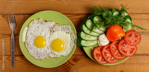 Fried eggs, pieces of vegetables, bread and fork on the table.