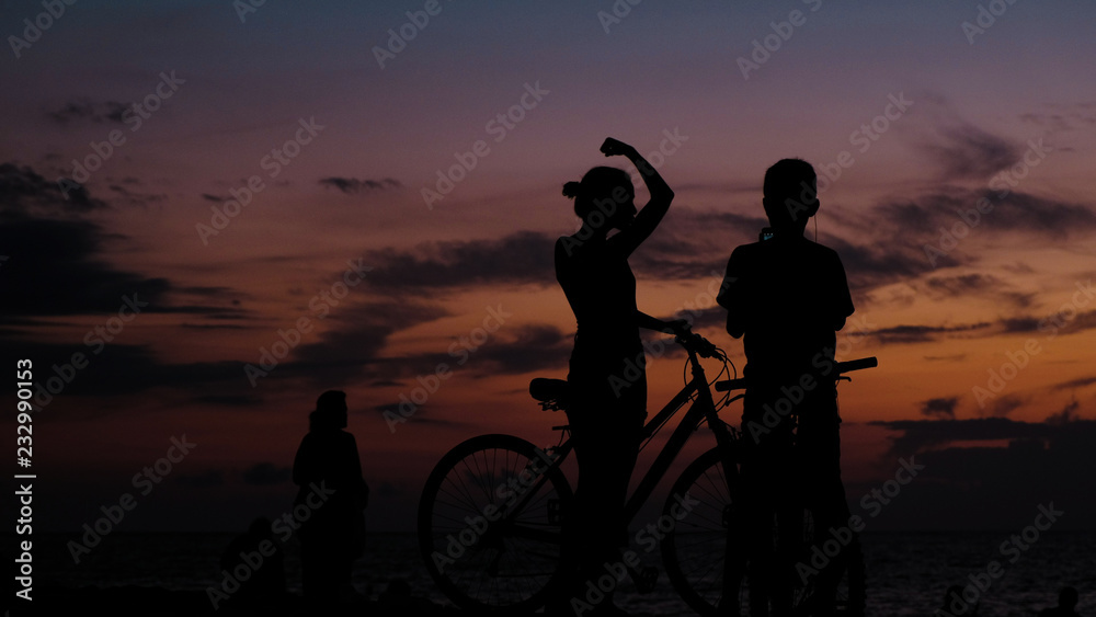 Silhouette of tourist photographing on the smartphone sunset on the sea