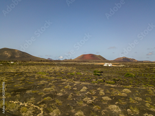 Vista aerea delle coltivazioni vinicole sui terreni vulcanici dell’isola di Lanzarote, pianure e colline nell’entroterra, vulcani all’orizzonte. Isole Canarie, Spagna. Produzione di vino photo