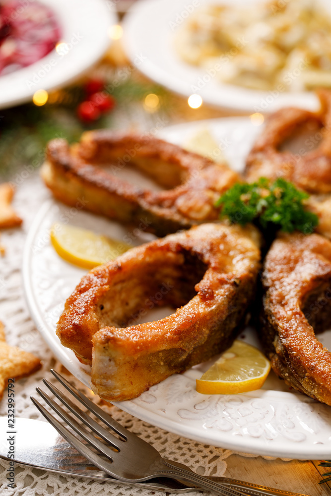 Fried carp fish slices on a white plate, close up. Traditional christmas eve dish. Polish Christmas food