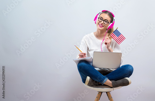 Young woman with USA flag using a laptop computer on a gray background photo