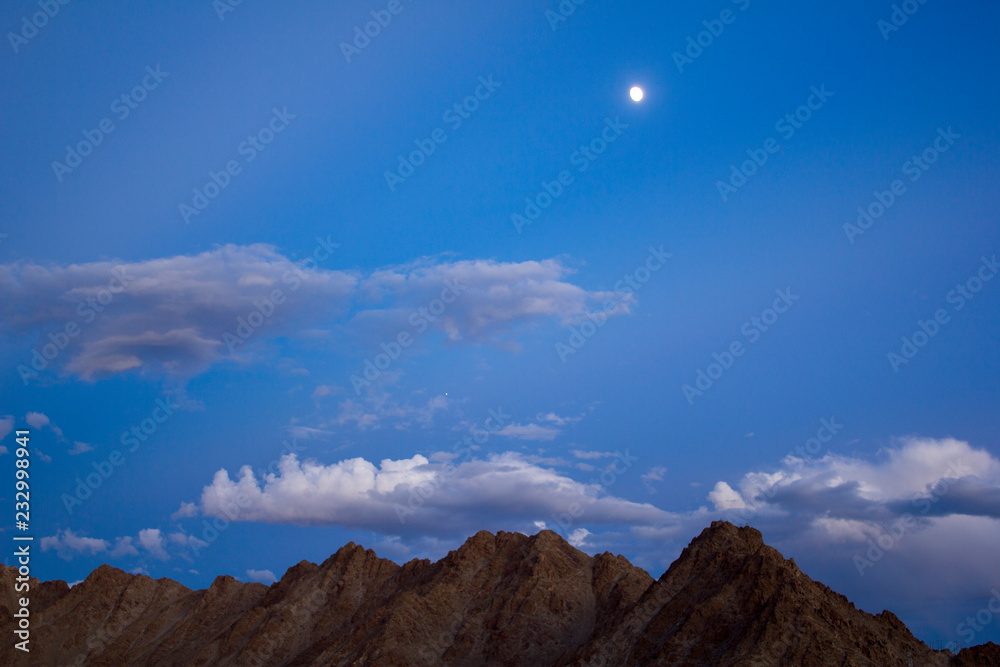 evening, night dark blue sky with clouds with stars and the moon over the desert mountains