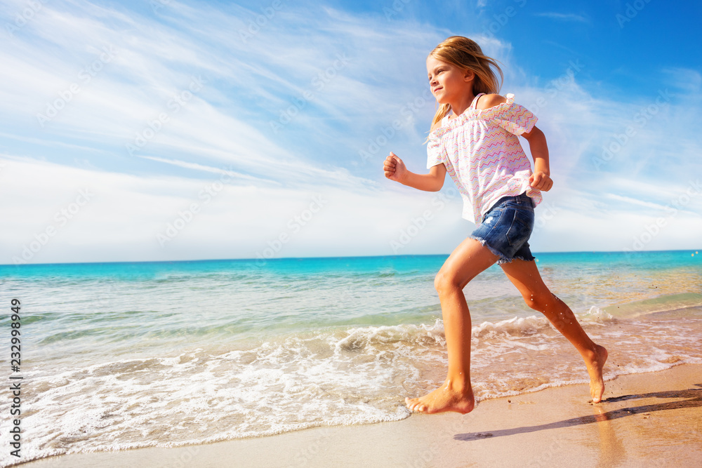 Beautiful girl running along sandy beach in summer Beautiful girl running along sandy beach in summer