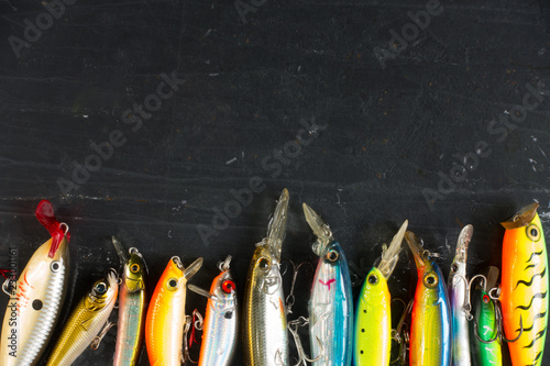 Various of fishing lures colorful on black stone wet background.