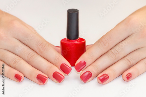 Nails Design. Hands With Red Manicure. Close Up Beautiful female hands with nail polish bottle. beauty concept