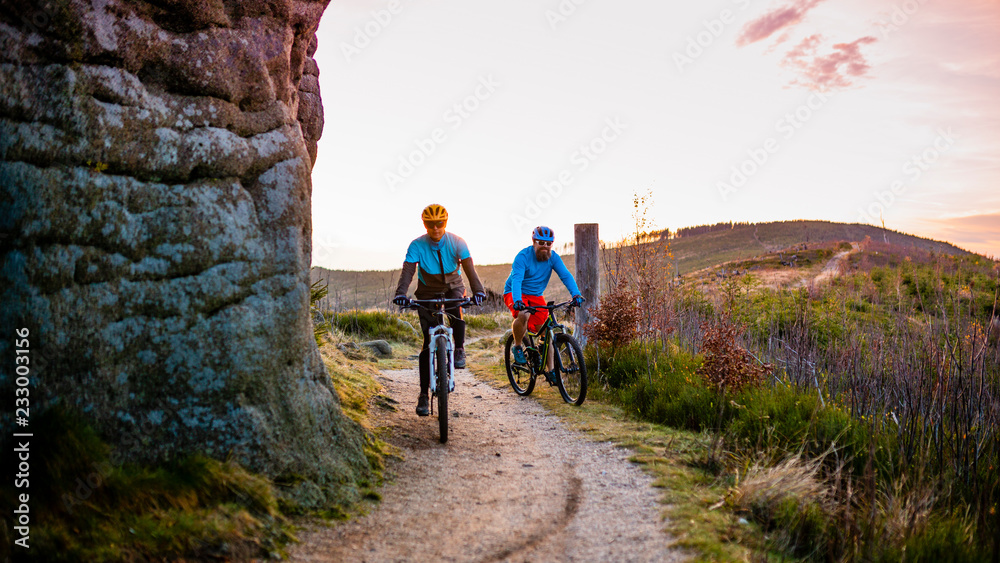 Fototapeta premium Cycling woman and man at Beskidy mountains forest landscape. Couple riding MTB enduro track. Outdoor sport activity.