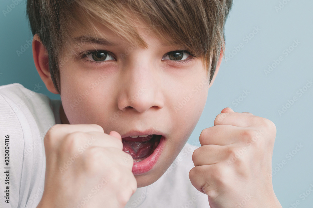 Boy screams and jokingly threatens with his fists in fighting stance Boy screams and jokingly threatens with his fists in fighting stance