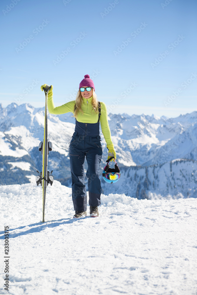 Young blonde woman with ski in the mountains at the sunny day