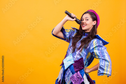 Beautiful young woman wearing funky clothes and singing microphone. Having fun