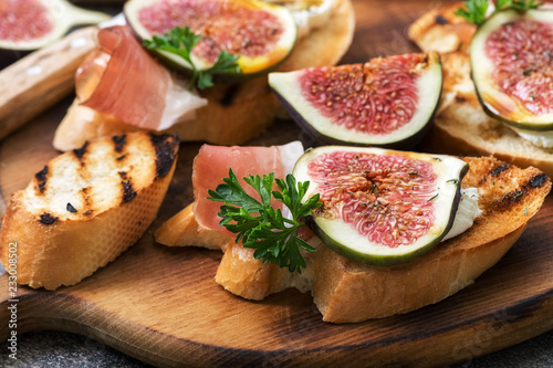 Closeup of prosciutto with figs on a cutting board. Selective focus.