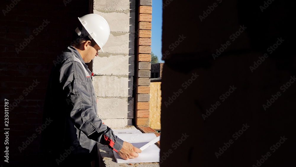 Man with paper draft in building under construction