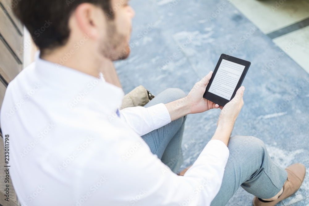 Fototapeta premium Man Reading Stories On E-Reader