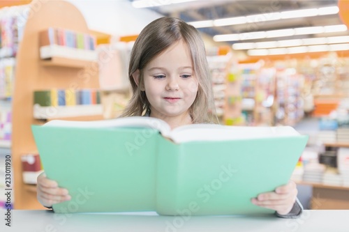 Adorable young girl reading a book