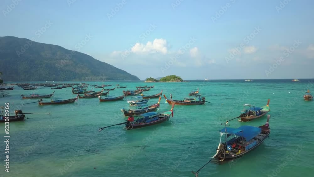 Top of traditional Thai boats, white sand beach, beautiful clear emerald sea, aerial drone view on tropical island, Ko Lipe, Thailand. Top of traditional Thai boats, white sand beach, beautiful clear emerald sea, aerial drone view on tropical island, Ko Lipe, Thailand.