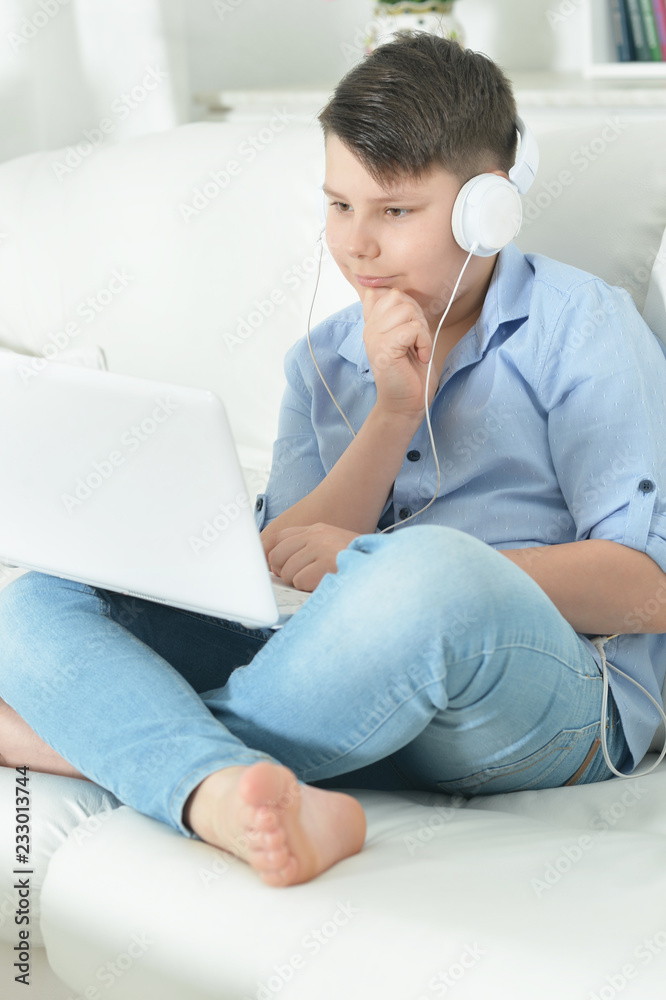 Portrait of boy with headphones using laptop