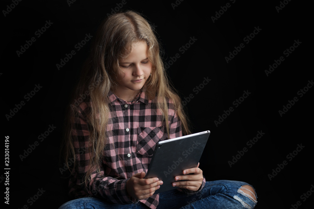 Cute young girl using a digital tablet on black background. Cute young girl using a digital tablet on black background.