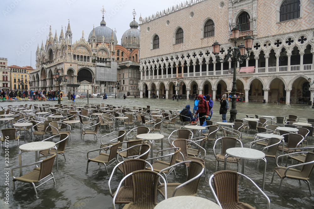 Naklejka premium Wenecja podczas przypływu: puste stoły i krzesła w wodzie na Placu św.Marka naprzeciwko Pałacu Dożów i Bazyliki San Marco