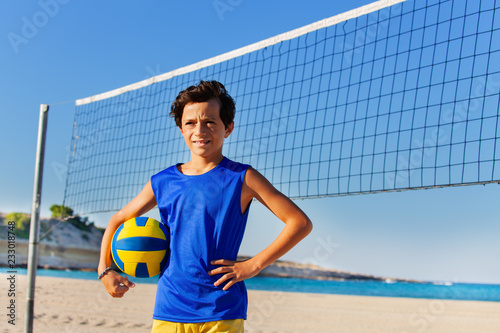 Beach volleyball player with ball next to the net