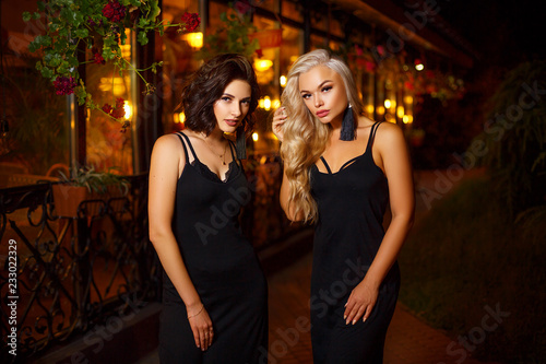 two beautiful young women posing on camera in the lights of the night city, the concept of beauty and fashion