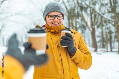 Φωτογραφία man bring coffee to go for friends in snowed city park
