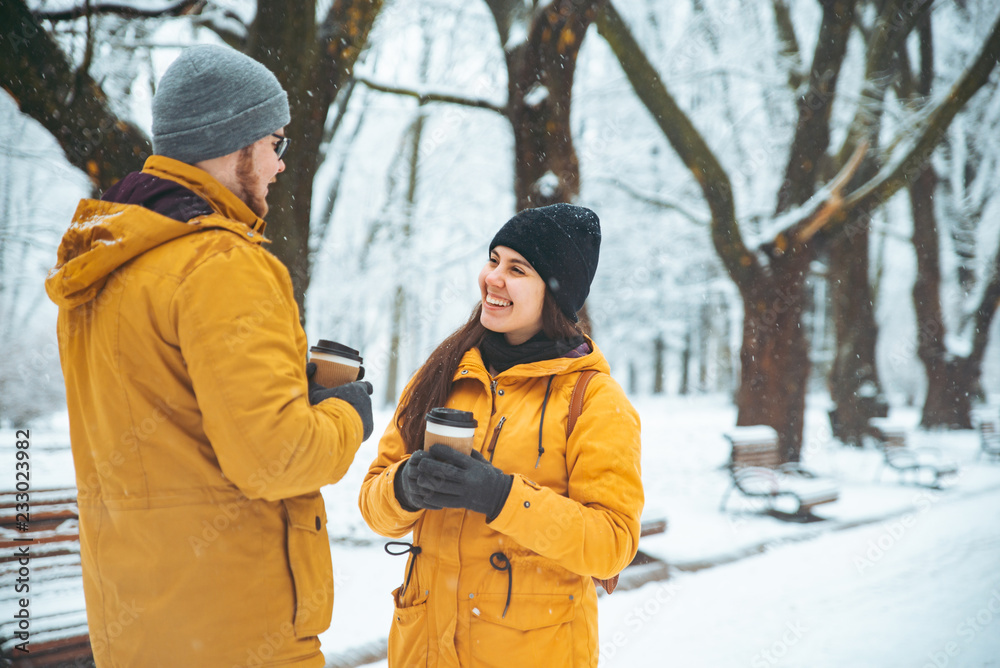 couple talking in city park man flirting with woman drinking coffee to go to warm up in winter snowed day couple talking in city park man flirting with woman drinking coffee to go to warm up in winter snowed day