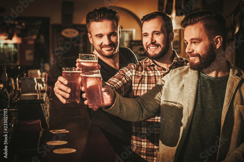 Photography Old friends having fun and drinking draft beer at bar counter in pub
