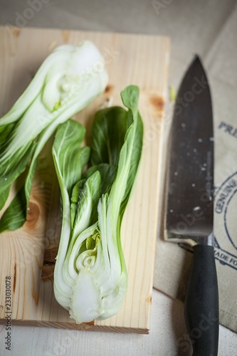 A hlaved bok choy on a wooden board with a knife photo