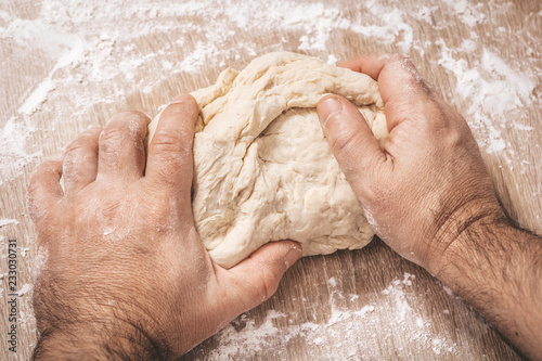 male chef kneads the dough