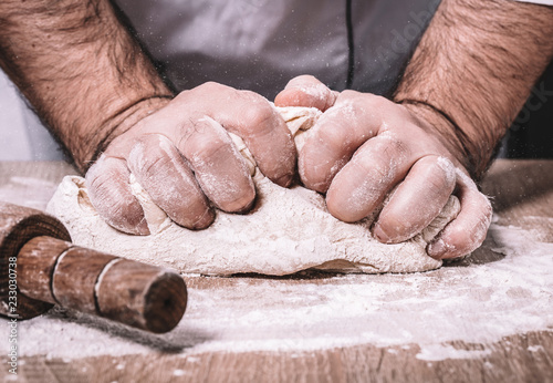 male chef kneads the dough