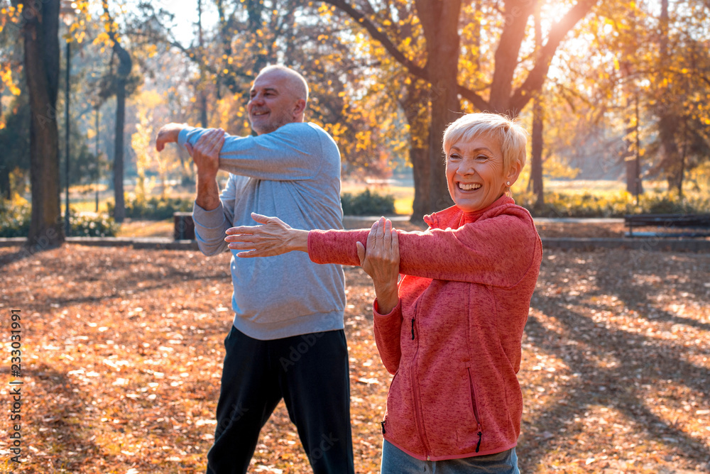 Fototapeta premium Active senior couple exercising outside in sunny autumn park