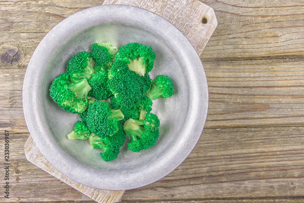 Fresh green broccoli in old metal bowl over rustic wooden desk on wooden background - healthy or vegetarian food concept Top view Fresh green broccoli in old metal bowl over rustic wooden desk on wooden background - healthy or vegetarian food concept Top view